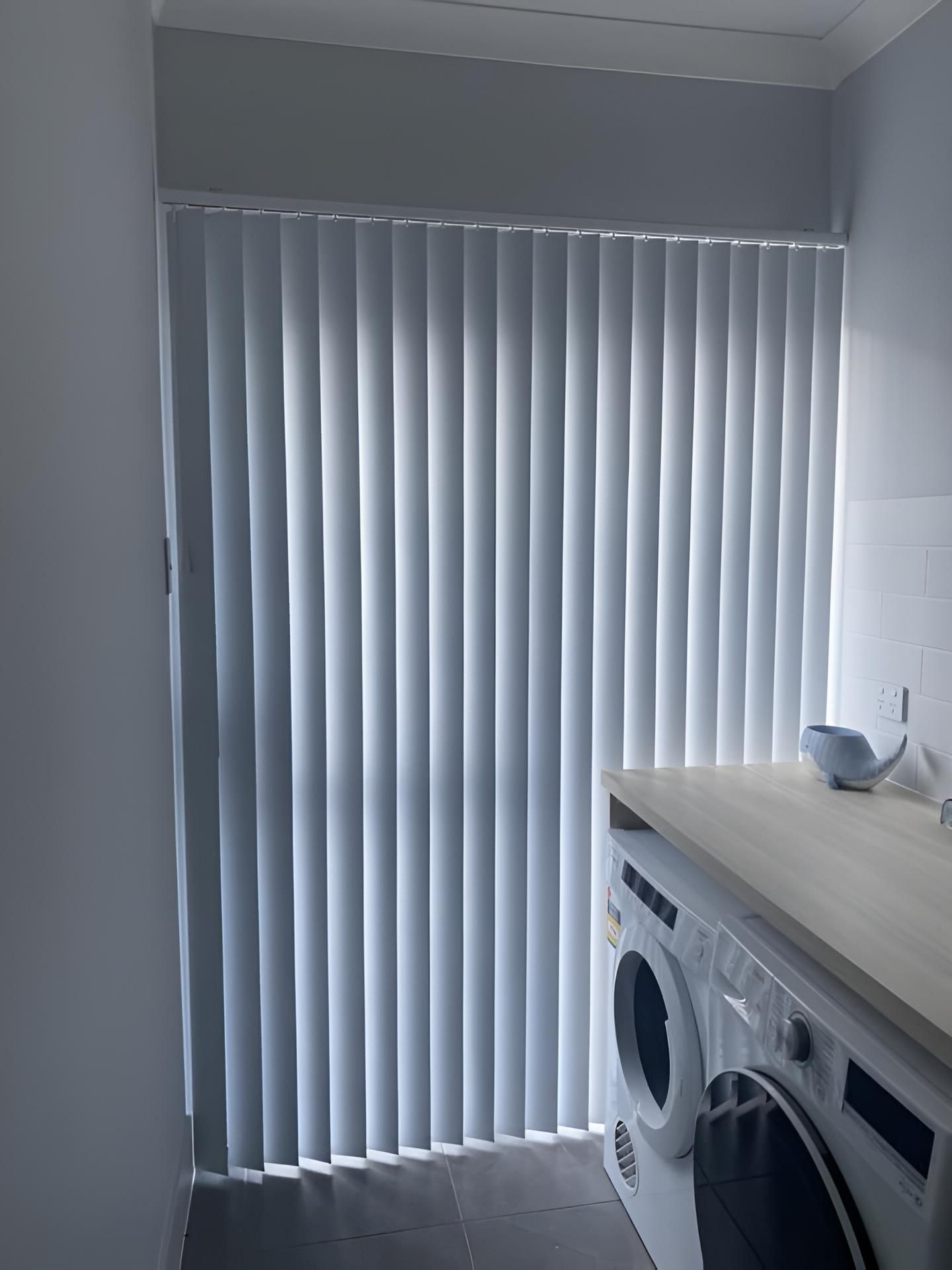 A Laundry Room With a White washing machine and White Vertical Blinds — Lismore Curtains & Blinds In Lismore, NSW