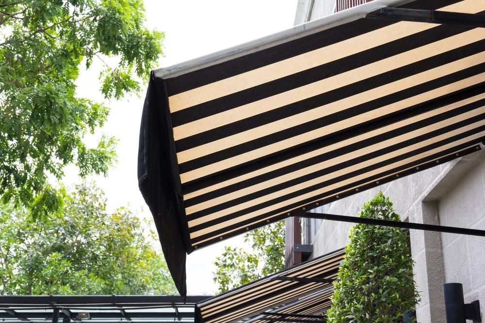 A Black and White Striped Awning From the Side of a Building — Lismore Curtains & Blinds In Casino, NSW