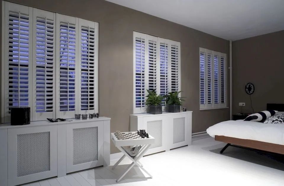A Bedroom With a Bed and Shutters on the Windows — Lismore Curtains & Blinds In Lismore, NSW