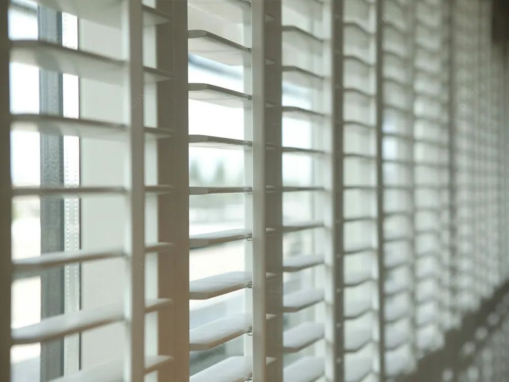 A Row of White Shutters on a Window in a Room — Lismore Curtains & Blinds In Lismore, NSW