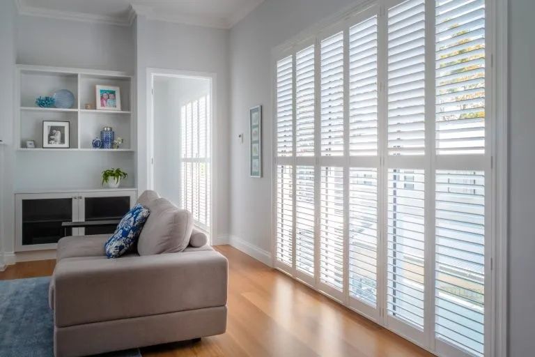 A Living Room With a Couch and Shutters on the Windows — Lismore Curtains & Blinds In Lismore, NSW