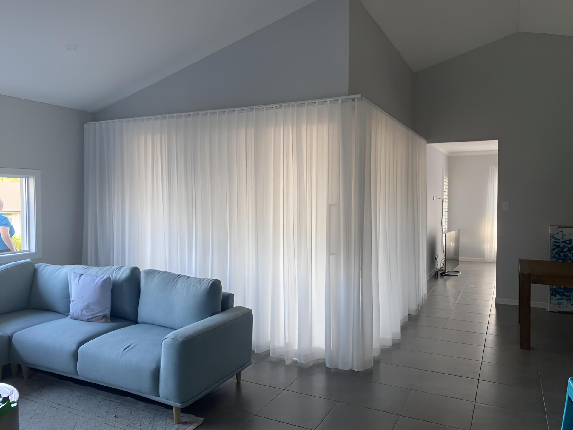 A Living Room With a Blue Couch and White Curtains — Lismore Curtains & Blinds In Lismore, NSW