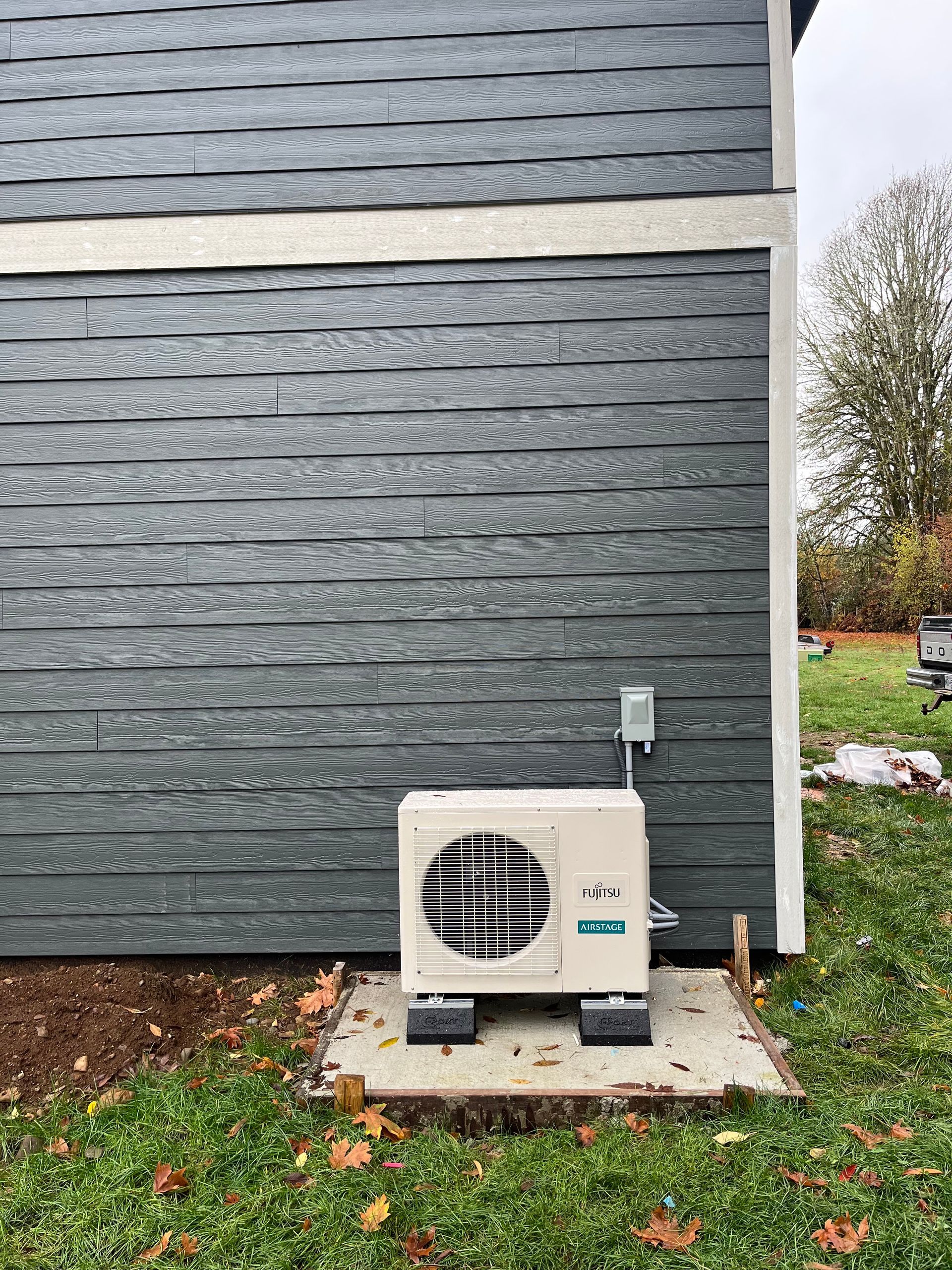 A small air conditioner is sitting on the side of a house.