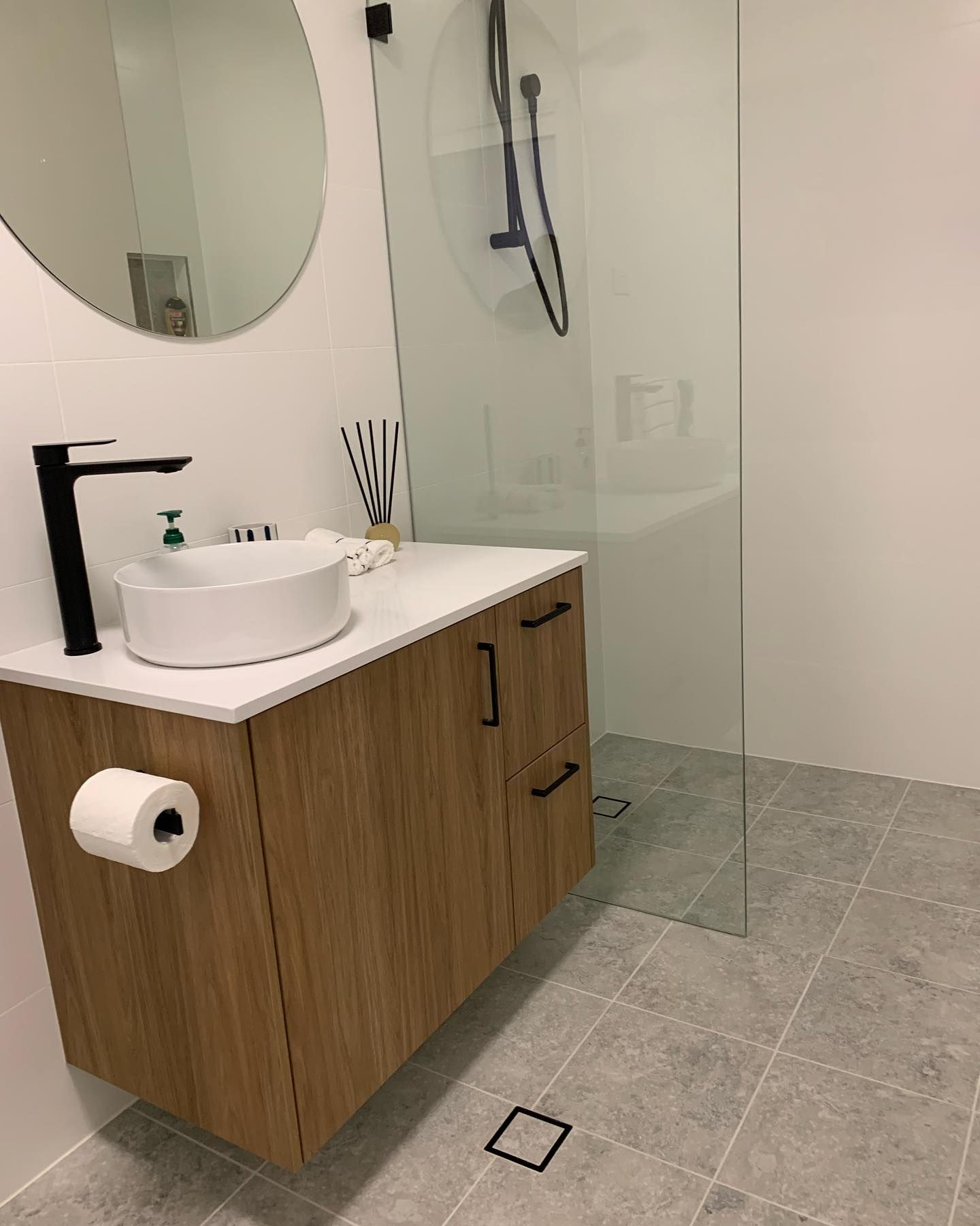 A Bathroom with a White Countertop, Wooden Cabinets, and Grey Tiles — The Kitchen Centre In Tuggerah, NSW