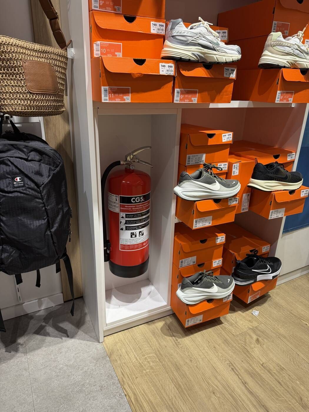 Brandslukker placeret i en reol mellem skoæsker i en Deichmann-butik