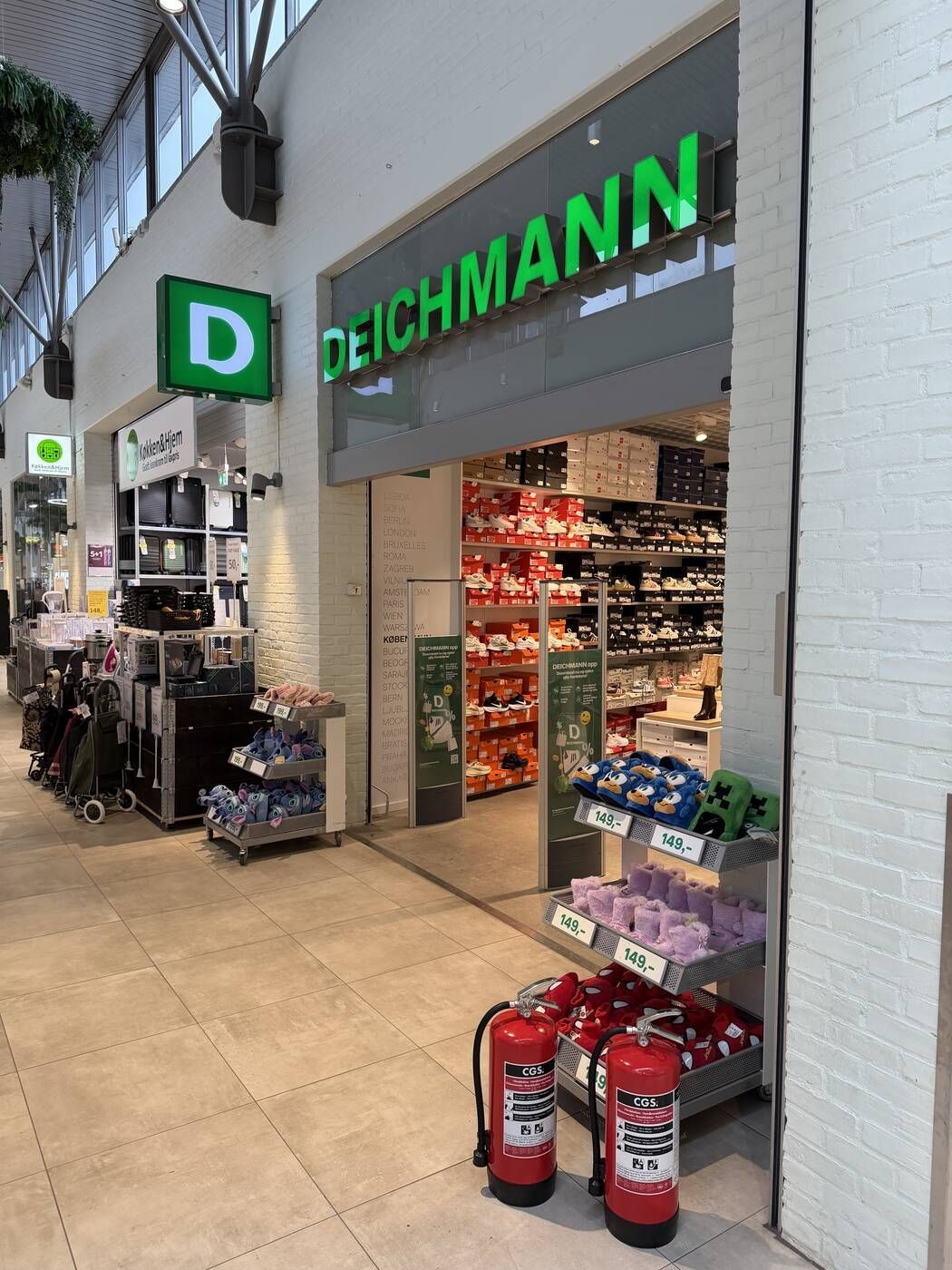 To brandslukkere ved indgangen til en Deichmann-butik i et storcenter