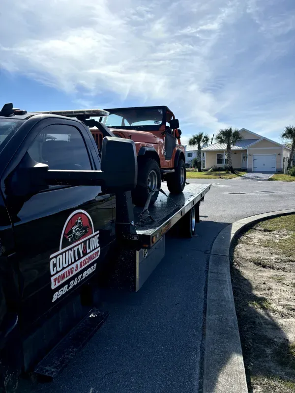 A jeep is being towed by a tow truck.