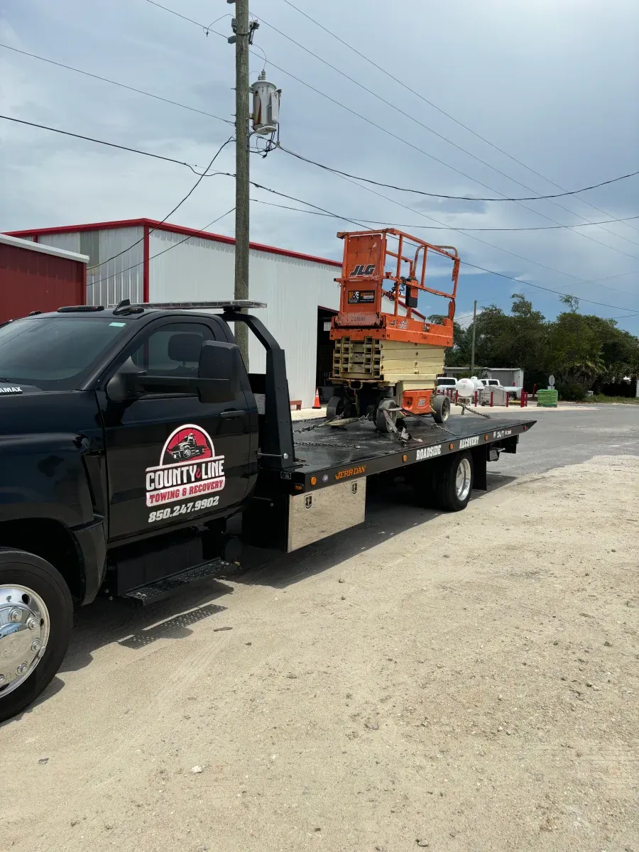 A tow truck with a lift on the back is parked on the side of the road.