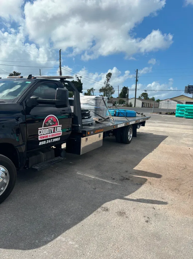 A black tow truck is parked in a parking lot.