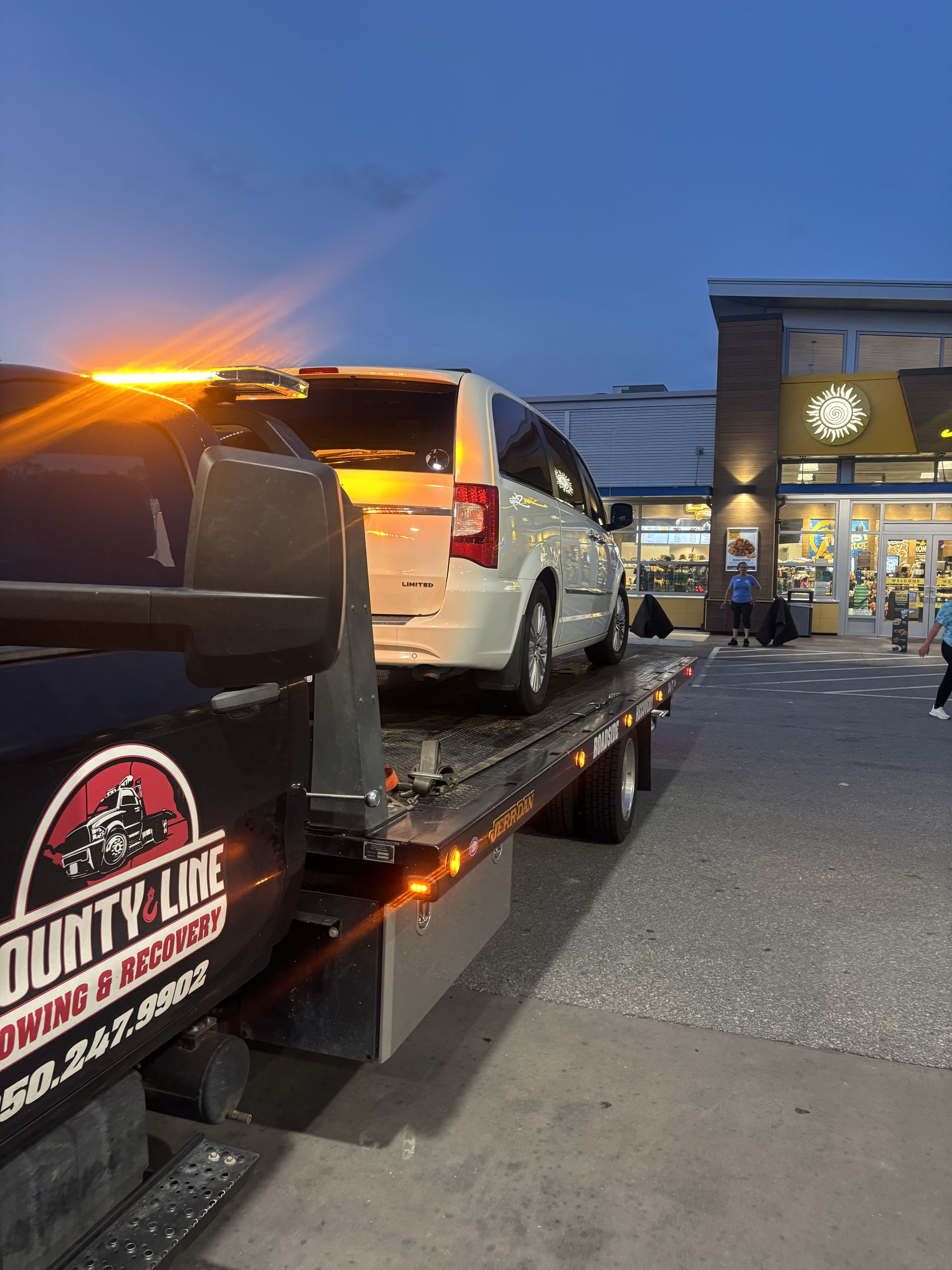 A white truck is sitting on top of a tow truck.