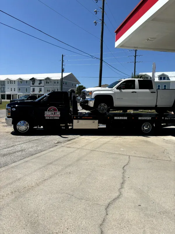 A white truck is being towed by a tow truck