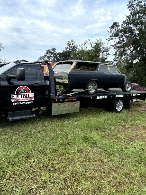 A tow truck is carrying a car on the back of it.