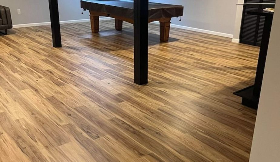Wood-patterned floor with a dark wooden pool table in a room with black legs and white walls