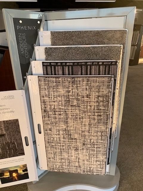 Display of patterned wallpaper sample books in a store, with various neutral and textured designs.