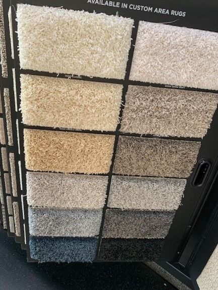 Carpet sample display with rows of beige, gray, and blue textured swatches on a black rack