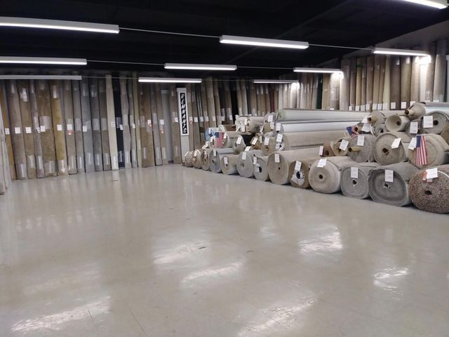 Empty industrial warehouse with rolls of material stacked along the right wall and a polished concrete floor