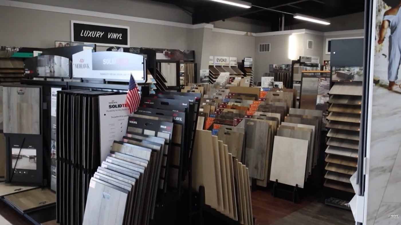 Store aisle with racks of flooring and tile samples displayed indoors