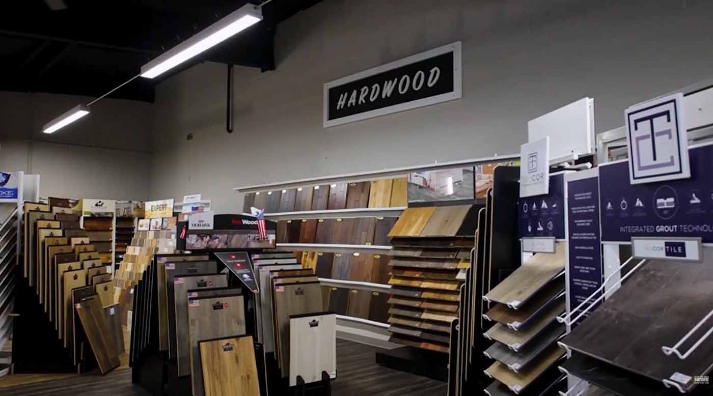 Flooring showroom with display racks of wood and tile samples under a