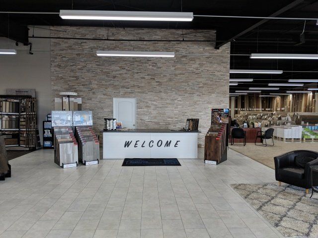 Lobby entrance with a white “WELCOME” desk, stone wall, tile floor, and lounge seating