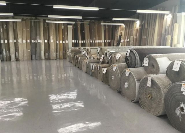 Warehouse aisle with stacked rolls of material and a shiny gray floor