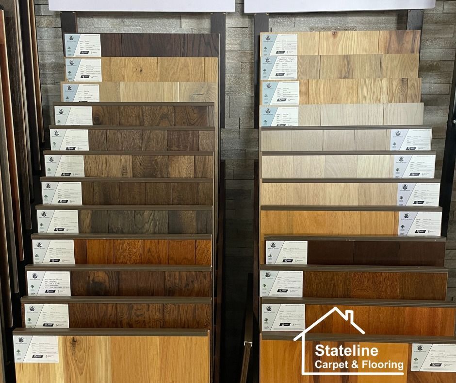 Two displays of wood and laminate flooring samples in a store, showing varied brown and gray finishes.