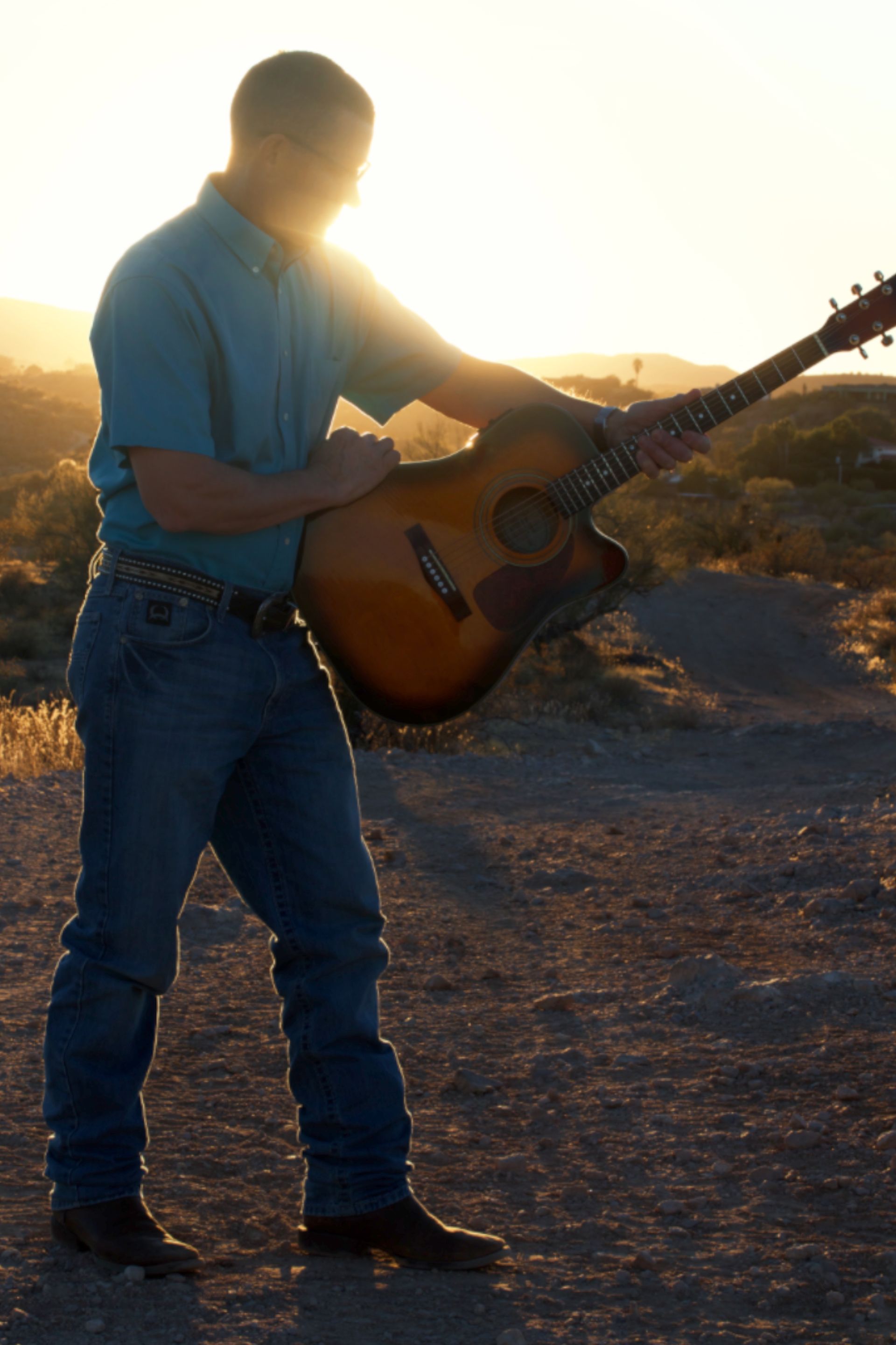 A man in a blue shirt is playing an acoustic guitar