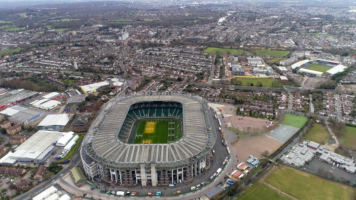 Aerial view of a large soccer stadium surrounded by dense city buildings and roads.