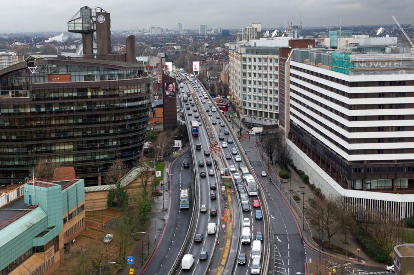 Aerial view of a busy city road with heavy traffic between office buildings on an overcast day
