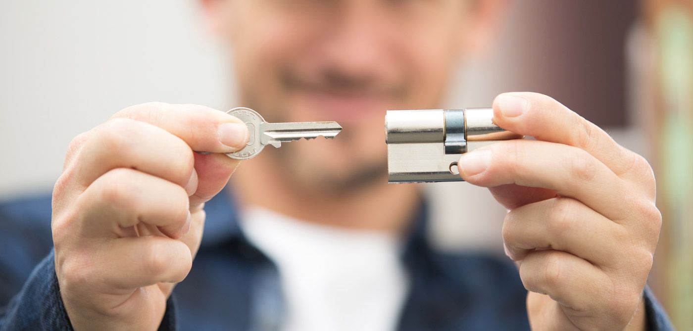 Person holding a key and a silver lock in front of a blurred background