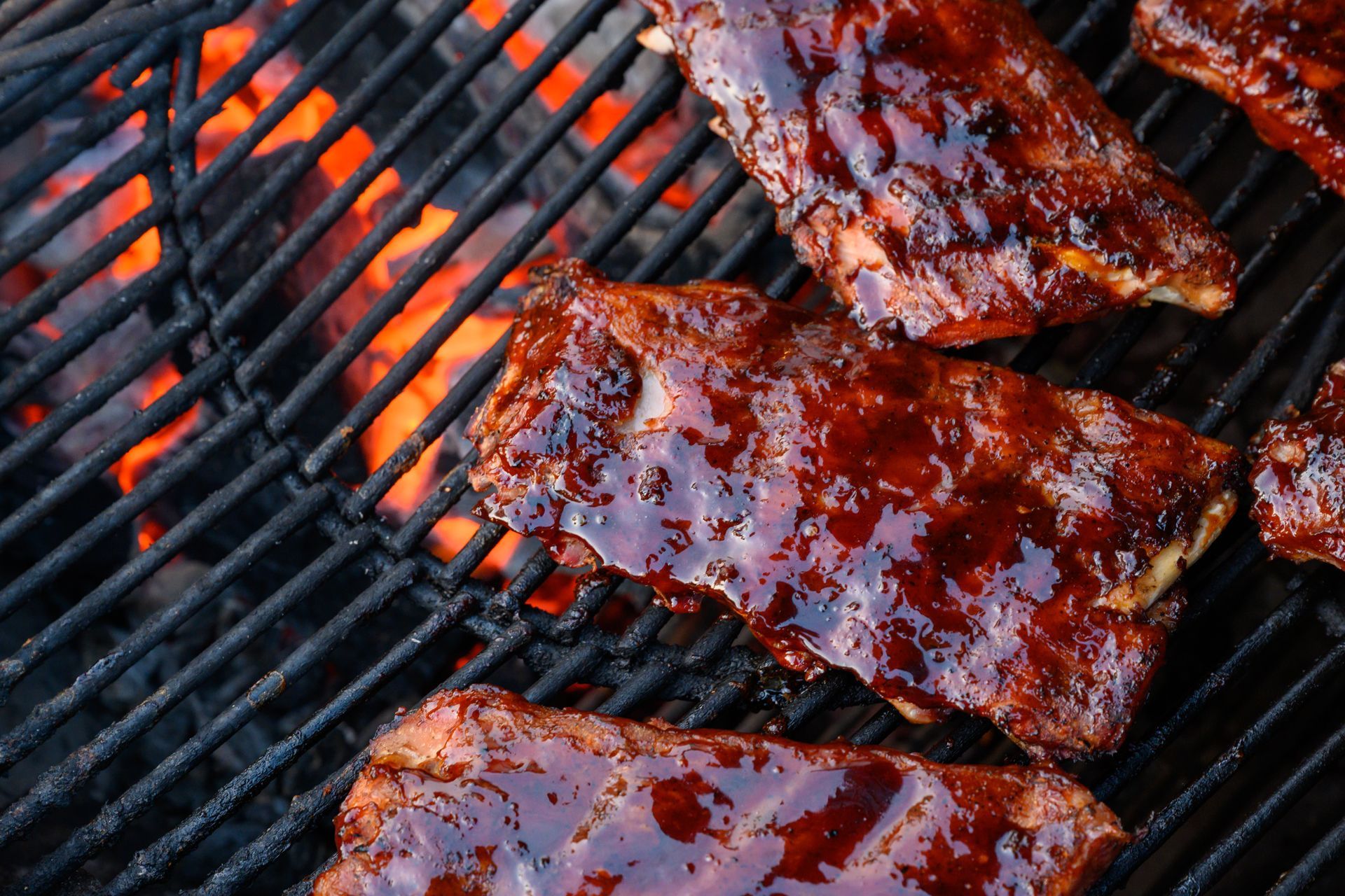 Ribs are cooking on a grill with flames