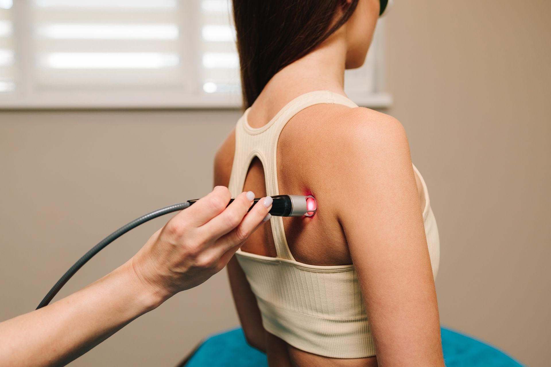 Therapist applying cupping to a woman’s upper back with a handheld device