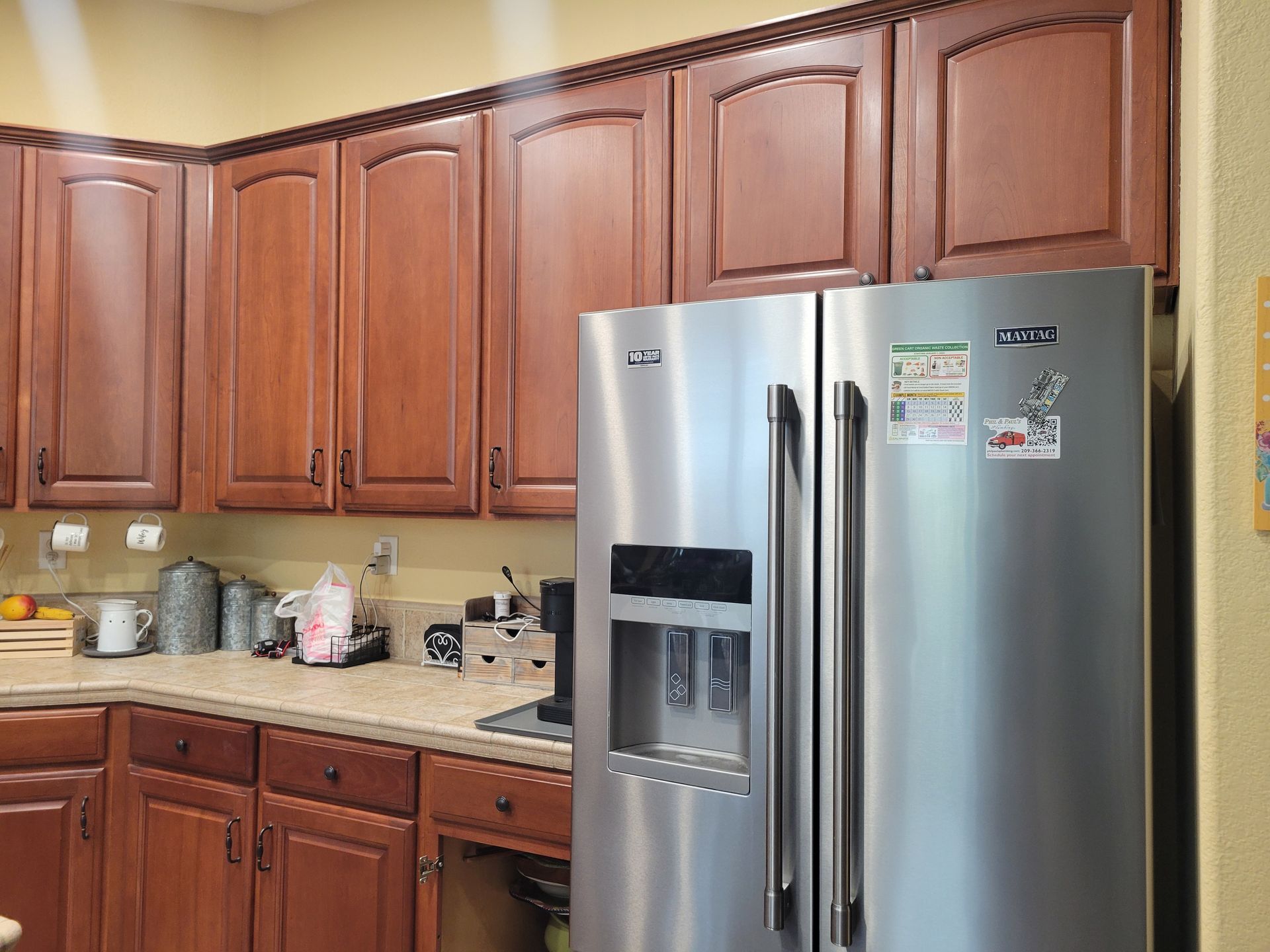 Kitchen with wooden cabinets, granite countertop, and stainless steel side-by-side refrigerator