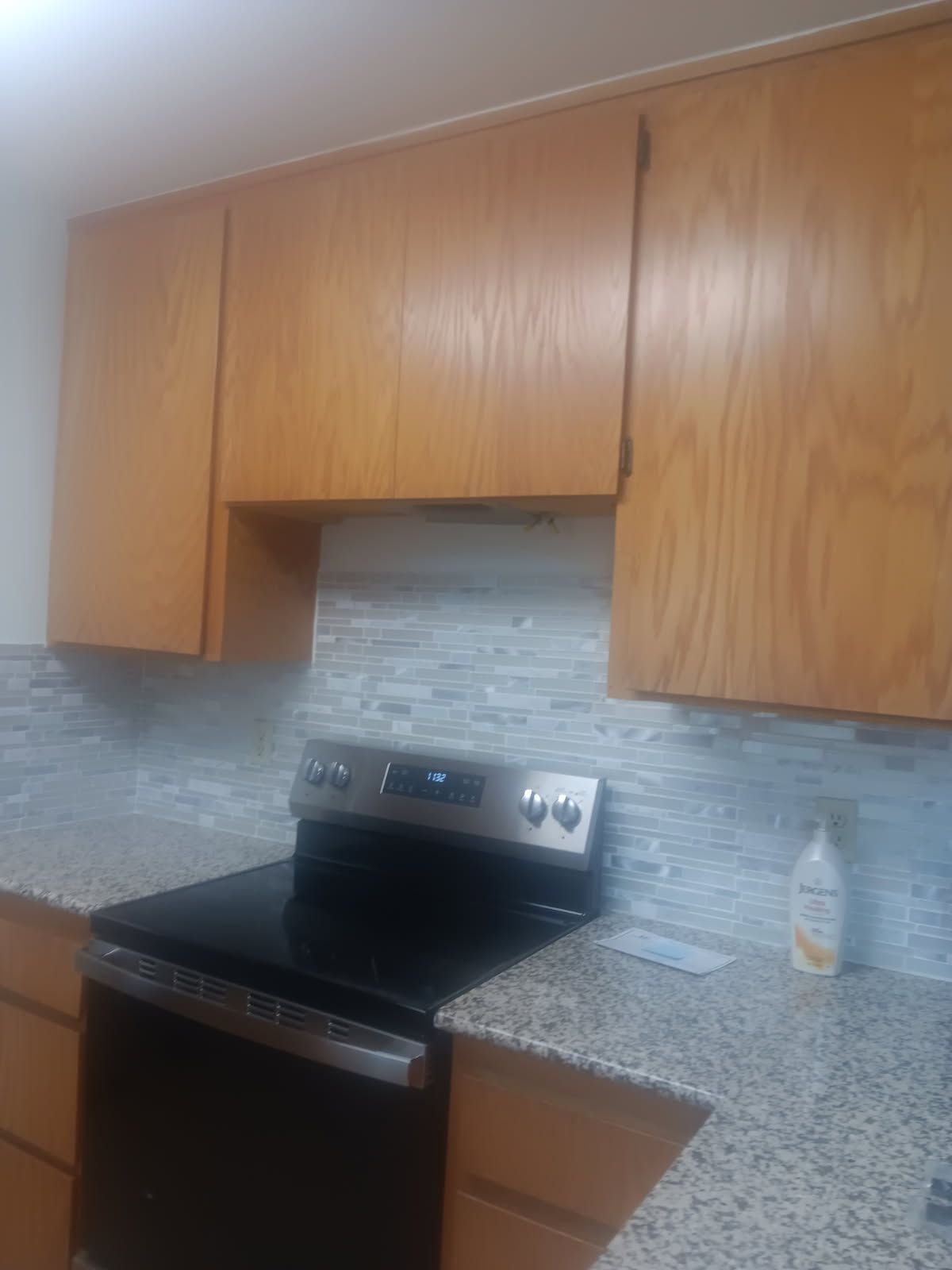 Kitchen with wooden cabinets, stainless steel stove, and speckled granite countertops.