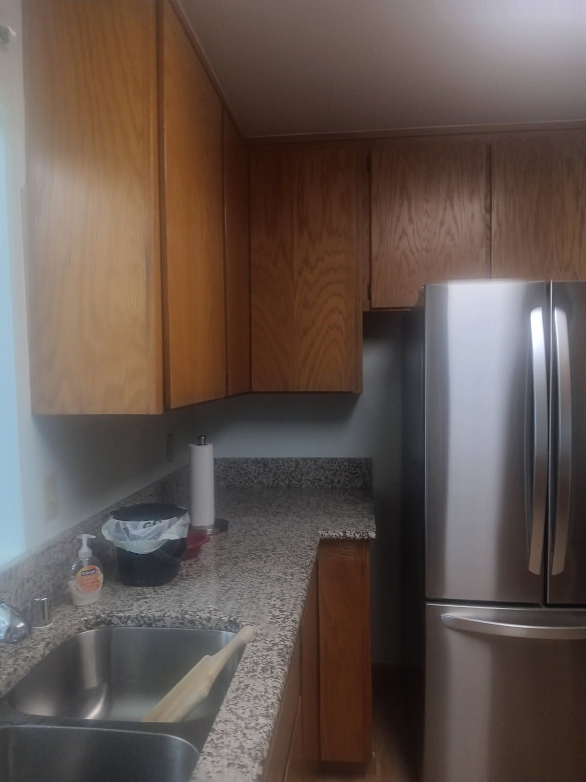 Small kitchen with wood cabinets, granite counter, stainless sink, and stainless refrigerator.