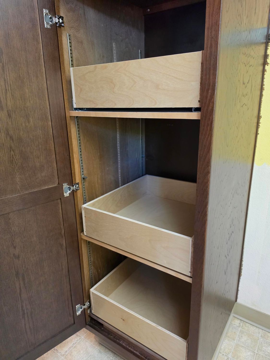 Open wooden cabinet with three shelves and a closed door, shown indoors.
