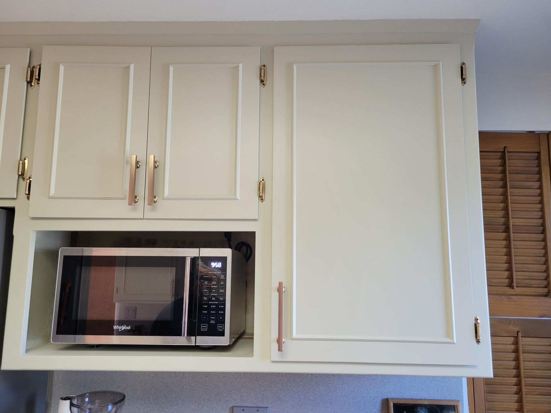 A kitchen with white cabinets and a stainless steel microwave