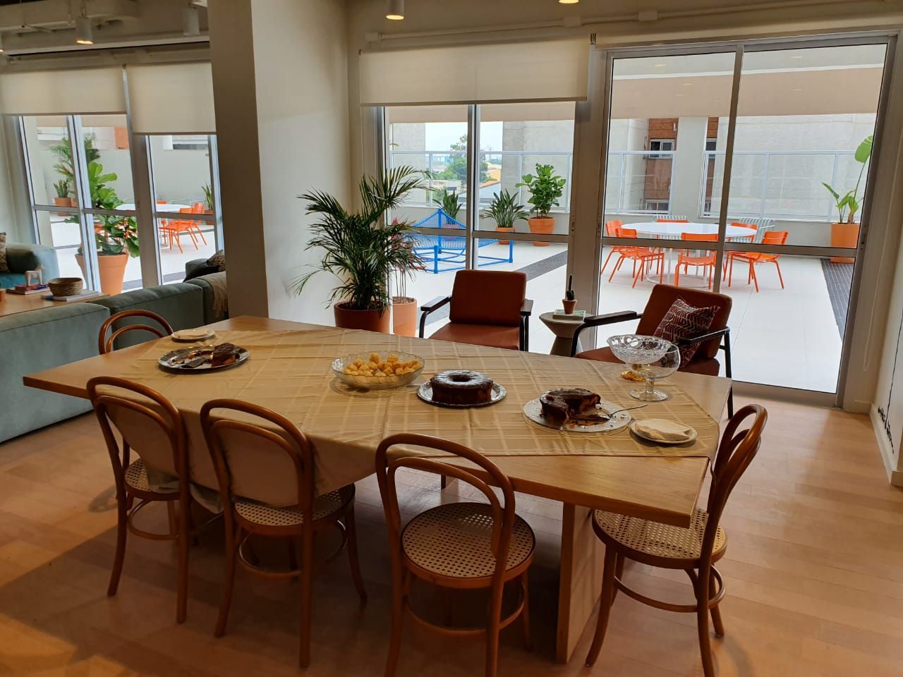 Sala de jantar com mesa oval de madeira, cadeiras e portas de correr que dão para um pátio iluminado.
