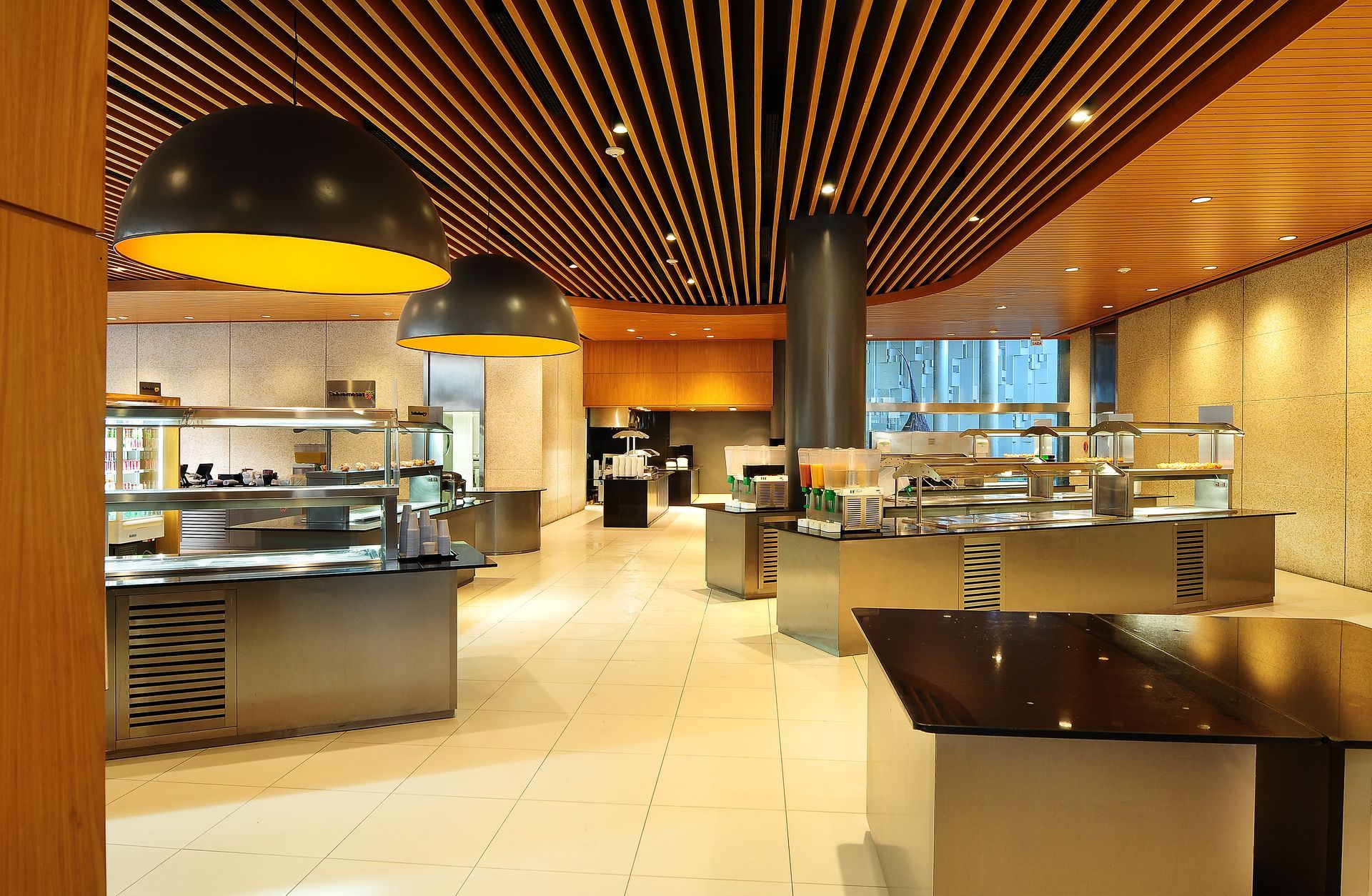 Restaurante buffet moderno com teto de madeira aconchegante, piso de azulejo branco e balcões de serviço em aço inoxidável.