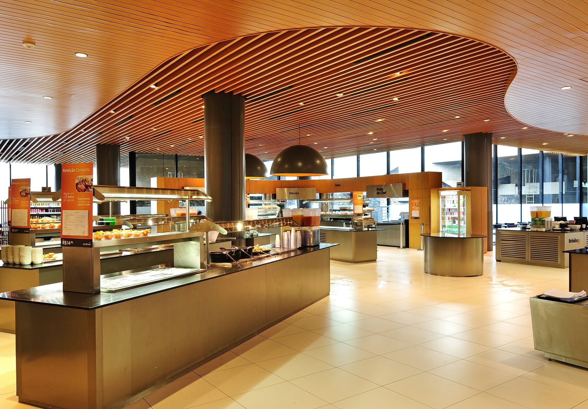 Cafeteria moderna com teto curvo de madeira, balcões de atendimento e iluminação aconchegante.