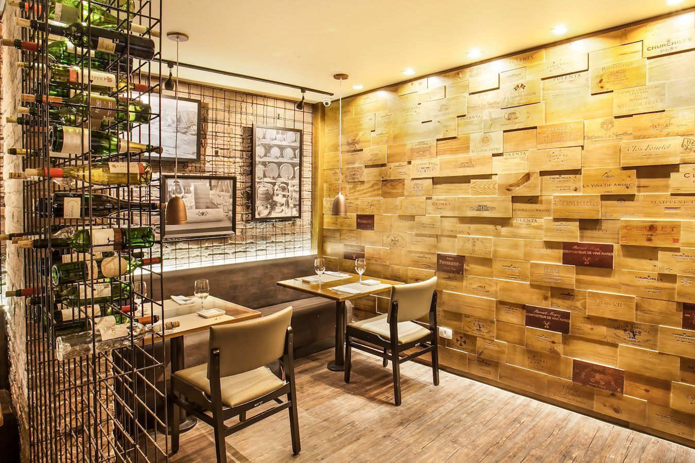 Interior aconchegante de restaurante com iluminação quente, parede revestida de madeira e pequenas mesas junto à janela.