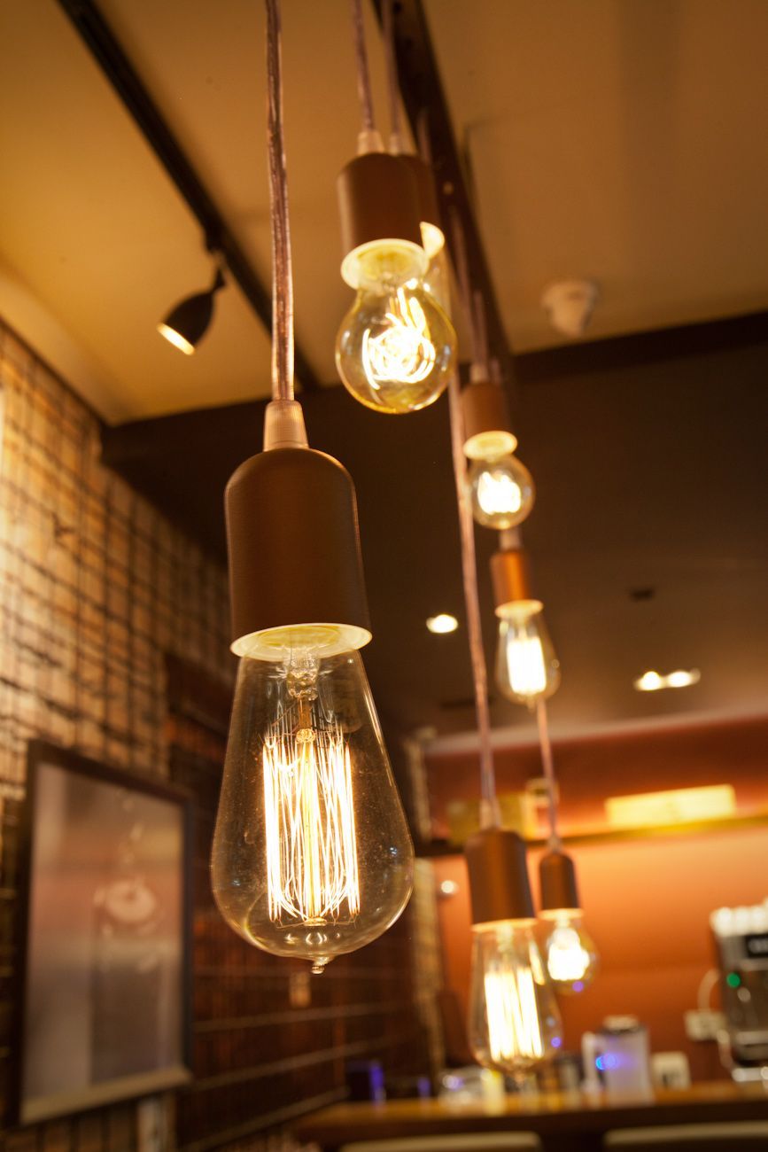 Fileira de lâmpadas Edison pendentes, com luz quente, em um aconchegante café ou bar.