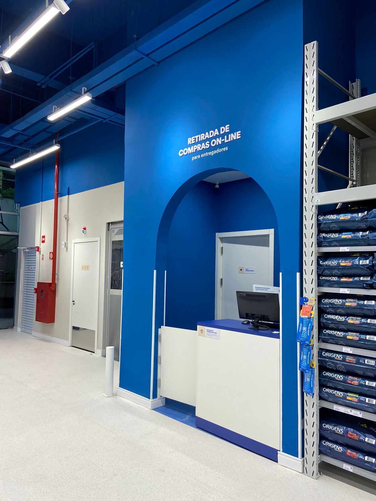 Interior de loja de varejo azul com balcão branco, prateleiras e uma grande porta em arco.