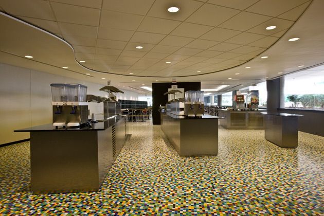 Refeitório luminoso com balcões de buffet, piso estampado e iluminação embutida aconchegante.