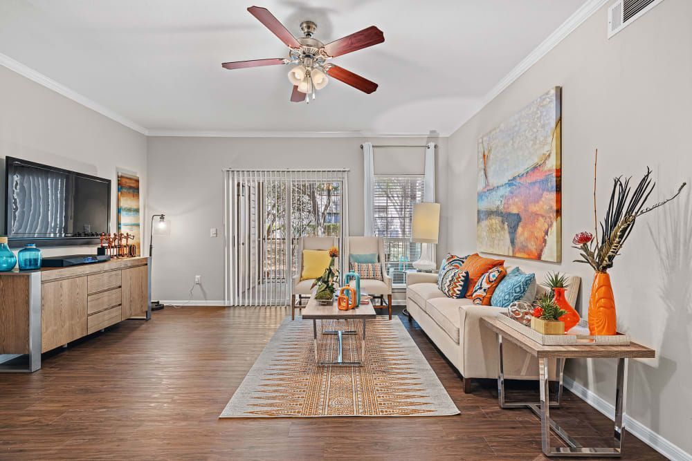 a living room with a couch, table, television, and ceiling fan at Marquis at Ladera Vista in Austin, TX.