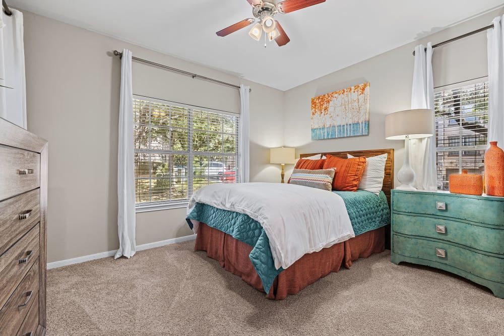 a bedroom with a bed, dresser, and ceiling fan at Marquis at Ladera Vista in Austin, TX.