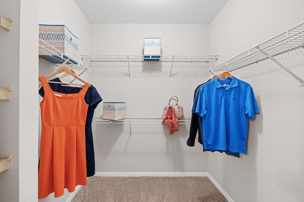 a walk-in closet with clothes hanging on racks and shelves at Marquis at Ladera Vista in Austin, TX.
