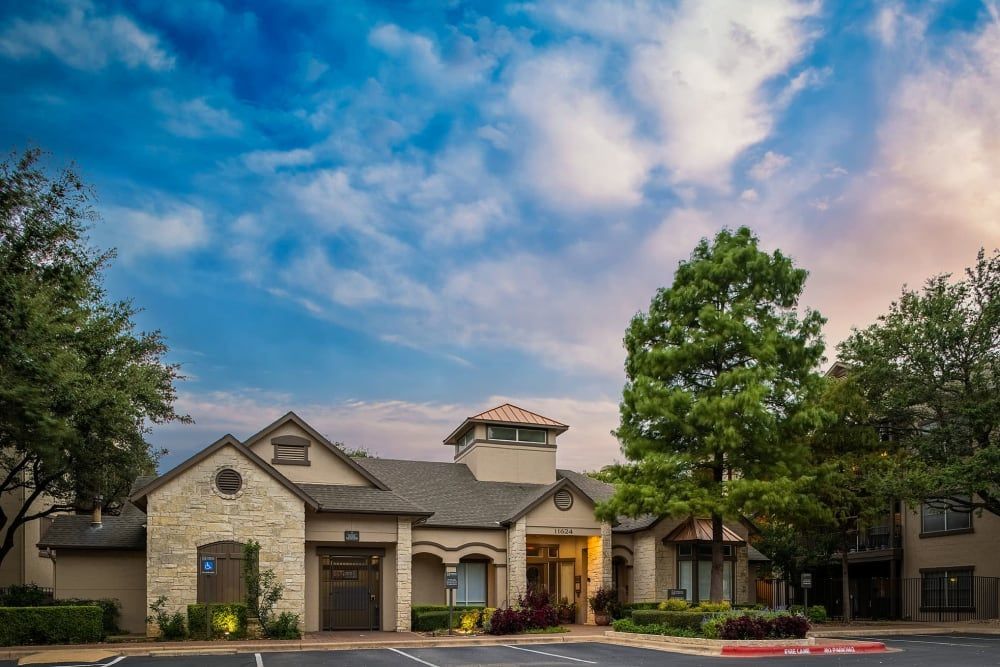 a large clubhouse with a lot of trees in front of it at Marquis at Ladera Vista in Austin, TX.