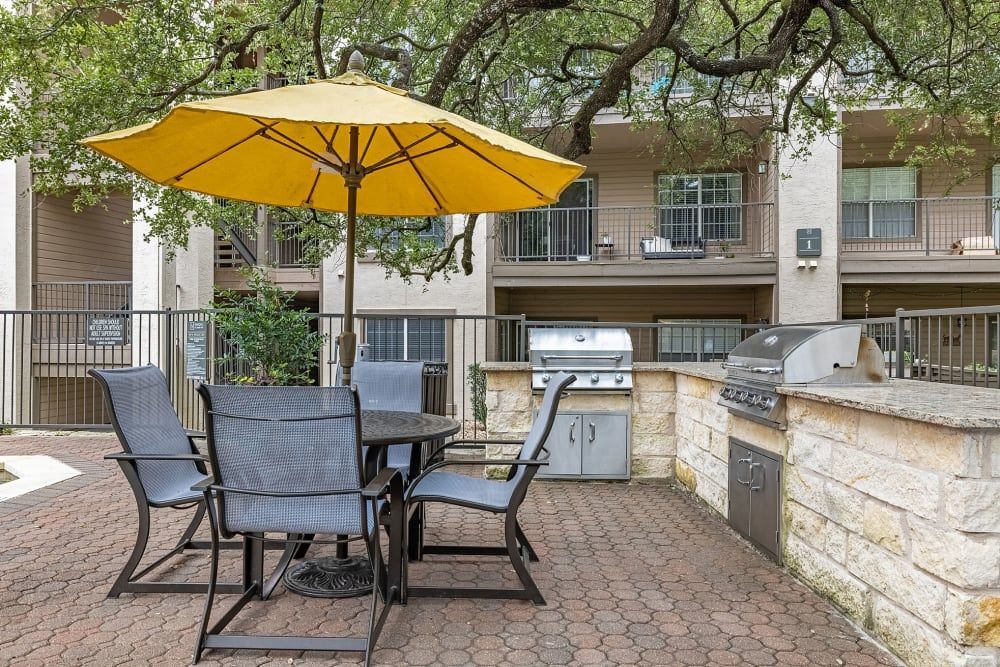 a yellow umbrella is sitting on a patio next to a table and chairs at Marquis at Ladera Vista in Austin, TX.
