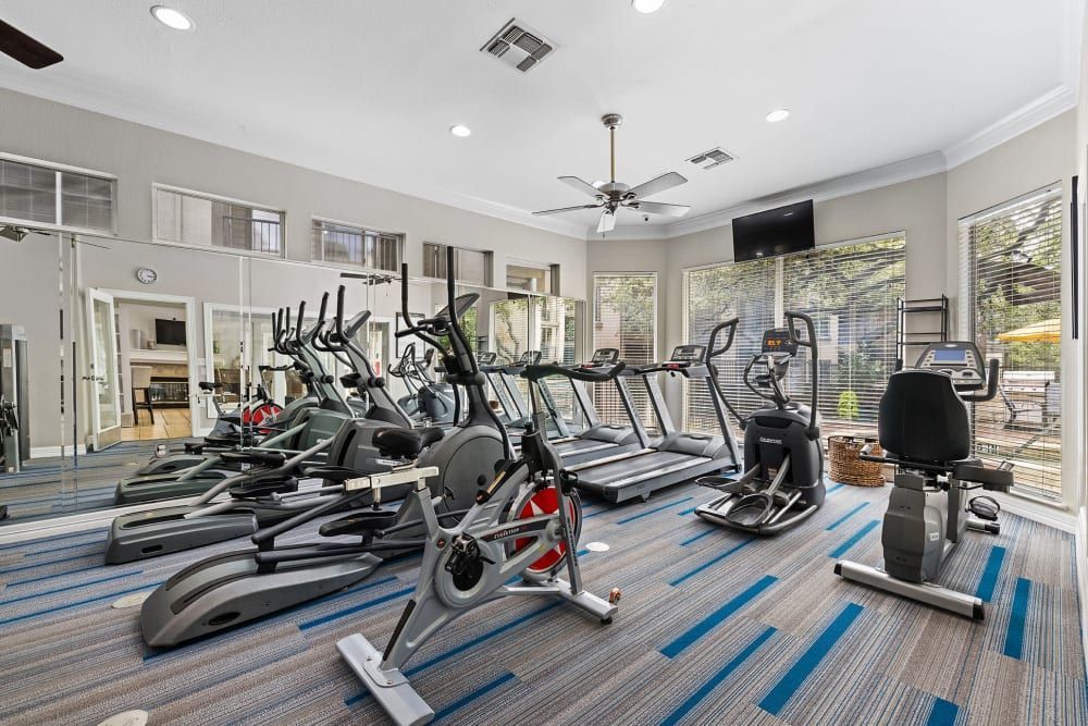 a gym with a lot of exercise equipment and a large mirror at Marquis at Ladera Vista in Austin, TX.