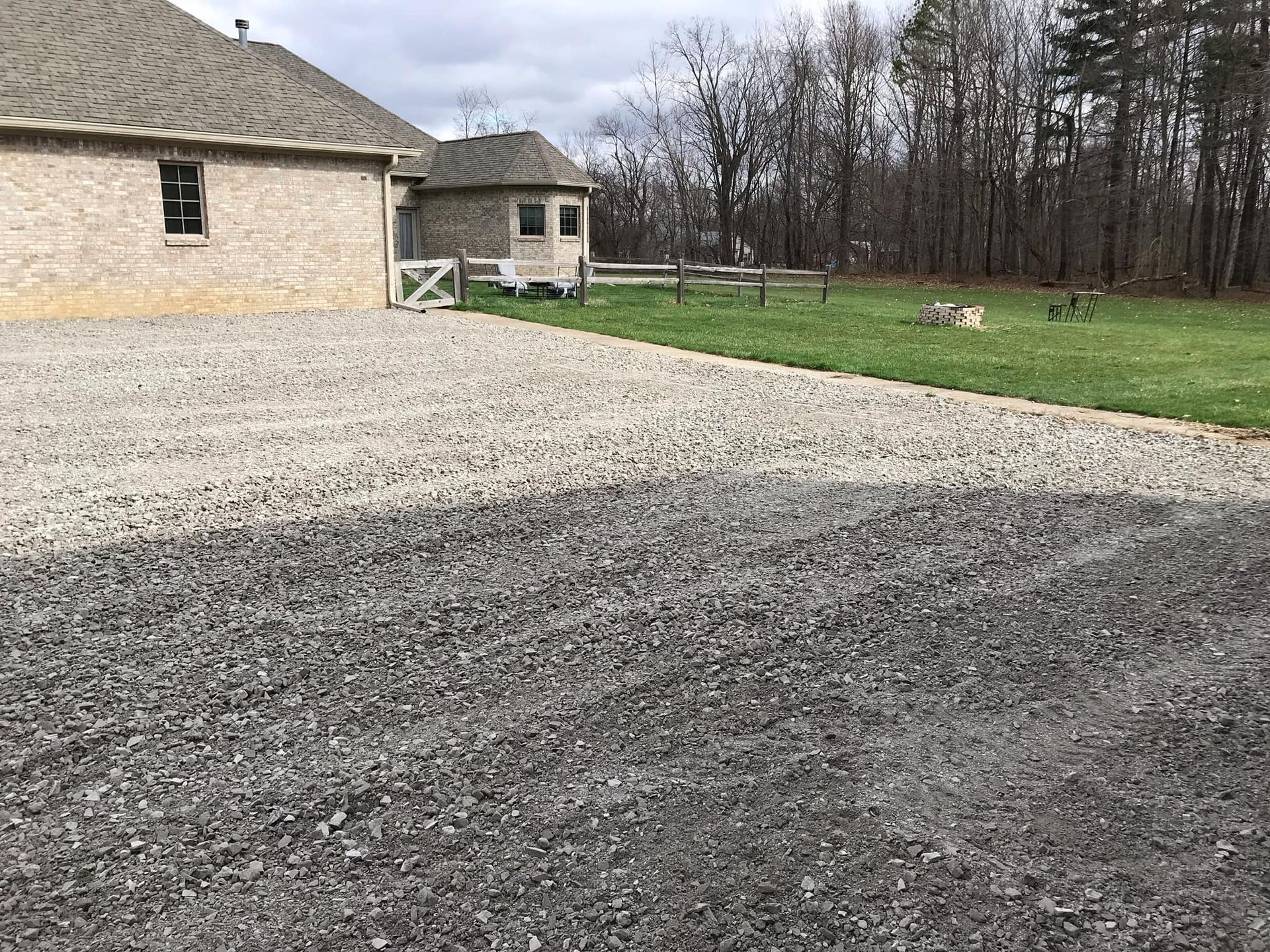 A gravel driveway leading to a house in the woods.